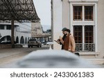 Two stylish men in coats using smart phone on city street.