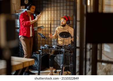 Two Stylish Men Playing Electric Drums, Composing Electronic Music At Small Recording Studio. Small Band Creating Or Practicing Music In A Home Studio. Caucasian And Hispanic Man Playing Together