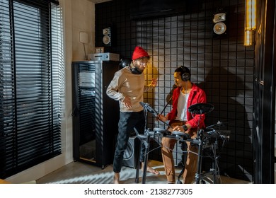 Two Stylish Men Playing Electric Drums At Small Recording Studio. Interior View On Home Studio. Caucasian And Hispanic Male Musicians Playing Electronic Music