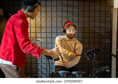 Two Stylish Men Playing Electric Drums, Composing Electronic Music At Small Recording Studio. Small Band Creating Or Practicing Music In A Home Studio. Caucasian And Hispanic Man Playing Together