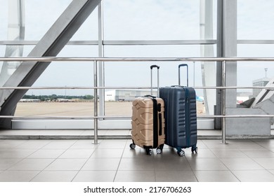 Two Stylish Plastic Luggage Suitcases Standing Near Panoramic Window At Airport, Blue And Beige Travel Bags Waiting In Terminal, Creative Shot For Transportration And Travelling Concept, Copy Space