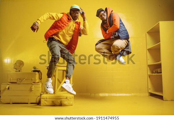 Two stylish\
rappers in studio, yellow\
background