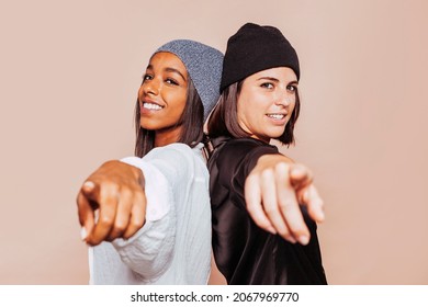 Two Stylish Smiling Woman Point Finger At You At Studio, Positive Mood. Cheerful Beautiful Young Woman Looking At Camera. Female Friends Having Fun Together. Copy Space.