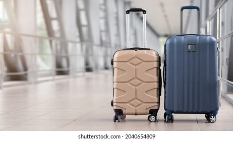 Two stylish suitcases standing in empty airport hall, unrecognizable traveller's luggage waiting in terminal, creative banner for air travels or vacation trip, panorama with copy space