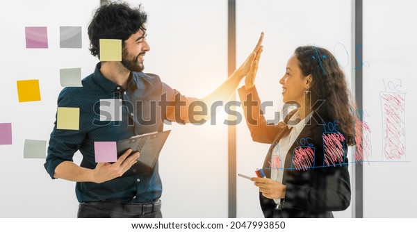 two success businessperson having high five after brainstorming and team discussing together for coporate planning in business office with light flare