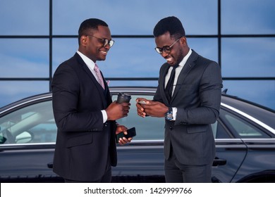 Two Successful African American Business Men Well Dressed Partners Standing Next To The Luxury Car On The Background Of The Offices Windows