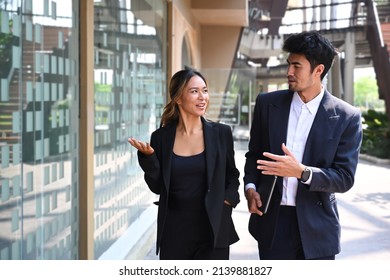 Two successful business colleagues having a discussion while walking outside modern office building. - Shutterstock ID 2139881827