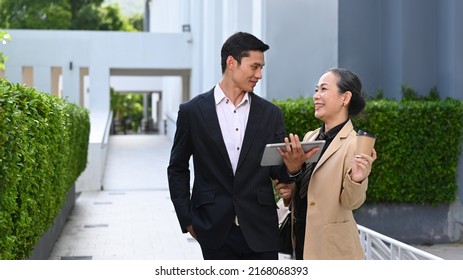 Two Successful Business People Walking Outside In Front Of Office Buildings