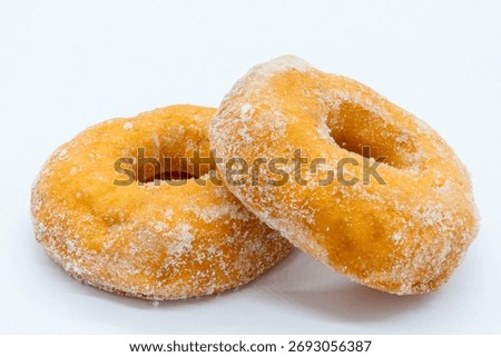 Two sugared crispie deep fried doughnuts one resting on the other. Good image for a cafe menu or delicatessen.