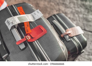 Two Suitcases At Airport With Heavy Tag Closeup. Checked Suitcase And Carry-on Luggage On The Curbside Ready For Travel With Address Tags.