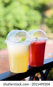 Two Summer Cocktails Standing Outdoors Over Green Grass. Cold Non-alcoholic Drinks With Ice To Go. Mojito Melon And Strawberry Lemonade Of Soda Water And Mint. Freshness And Holidays.