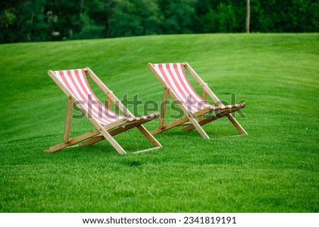 Two sun loungers on a fresh green lawn. A beautiful summer evening.