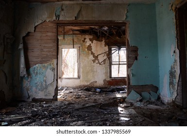 Two sunlit windows viewed through two rooms of a dilapidated abandoned farm house