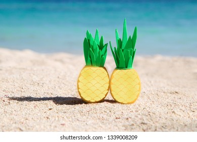 Two sunny easter eggs with pineapple leaves on the sandy beach near the ocean