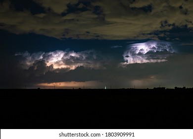 Two supercell thunderstorms are illuminated by lightning flashes at night