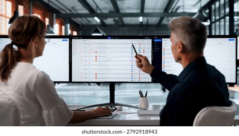 Two IT Support Specialists Work Together Using Software On Computer Screens.