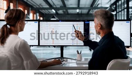 Two IT Support Specialists Work Together Using Software On Computer Screens.