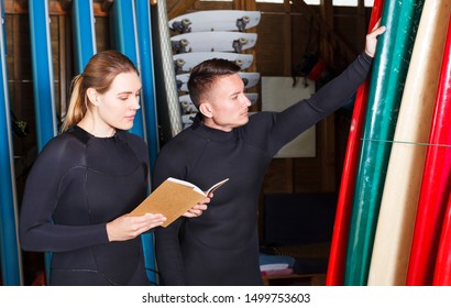 Two surf instructors making complete list of surfboards suitable for rent in surf club - Powered by Shutterstock