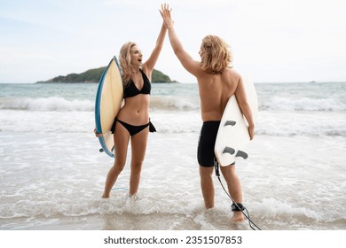 Two surfers giving high five on the beach. Two surfers having fun on the beach. - Powered by Shutterstock