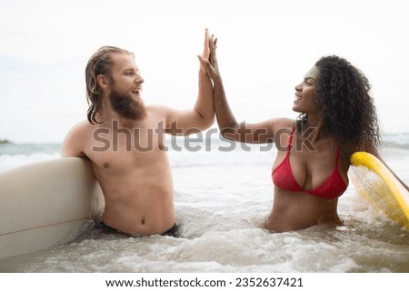 Two surfers giving high five on the beach. Two surfers having fun on the beach.