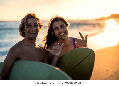 Two surfers prepares to hit the waves as they standing on the beach with their surfboards. - Powered by Shutterstock