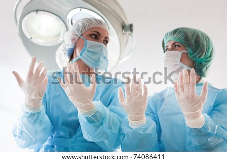 Two surgeons in coats,masks,caps and sterile gloves