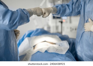 Two surgeons giving five each other ready for an operation, close-up. Concept of teamwork and success in surgery - Powered by Shutterstock