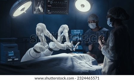 Two Surgeons Observing High-Precision Programmable Automated Robot Arms Operating Patient In High-Tech Hospital. Robotic Limbs Performing Complex Nanosurgery, Doctors Looking At Vitals On Monitor.