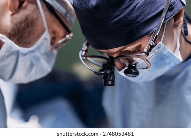 Two surgeons performing an operation with full concentration in a sterile operating room. Concept of medical technologies and surgery.
