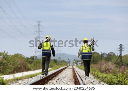 two surveyors hold the tripod of a geography camera on the railway 