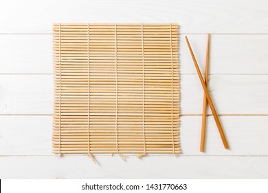 Two Sushi Chopsticks With Empty Bamboo Mat Or Wood Plate On Wooden Background Top View With Copy Stace.