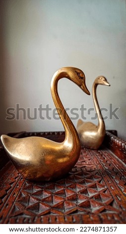 Two swans made of copper are kept in a wooden tray for the show piece in the living room. Art piece.