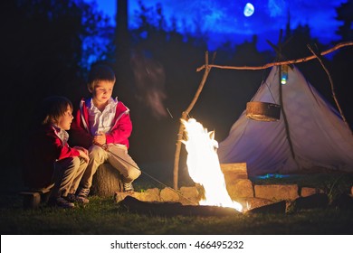 Two sweet boys, sitting around the campfire after sunset, listening scary stories