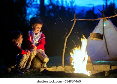 Two sweet boys, sitting around the campfire after sunset, listening scary stories