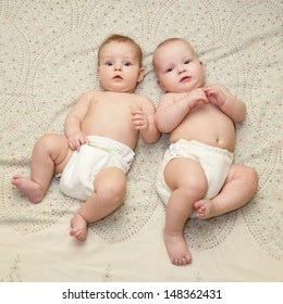 Two sweet chubby babies in diapers laying on the sheet