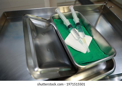 Two Syringes In Tray With Sterile Gauze On Stainless Steel Cart.