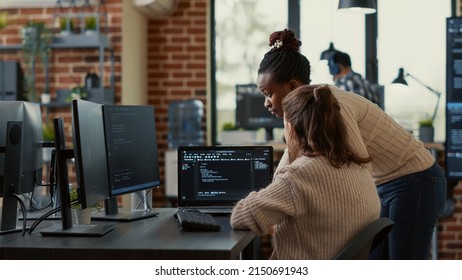 Two System Engineers Analyzing Source Code On Laptop Looking For Errors On Screen While Sitting At Desk. Team Of App Developers Working On Group Project For Ai Online Cloud Computing Project.