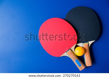Two table tennis or ping pong rackets and balls on a blue table 
