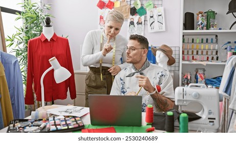 Two tailors, a man and a woman, collaborate in a bustling fashion design studio, surrounded by fabric and sewing tools. - Powered by Shutterstock