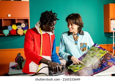 Two Tailors Working On Ideas And Talking About Projects, Small Business People Working Together In A Hand Made Dress Tailor Workshop, Concept Of Social Integration Between Different Cultures