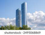 Two tall buildings with a cloudy sky in the background. The buildings are very tall and have a modern design