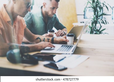 Two Tattoo Artist Working Wood Table Laptop Modern Interior Design Loft.Coworkers Work Office Studio.Hipsters Contemporary Notebook Digital Tablet New Art Project.Blurred Background. Business Startup