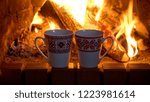 Two tea cups on the background of a burning fireplace