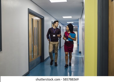 Two Teachers Are Talking In The School Hall As They Walk To Their Next Lesson Together. 