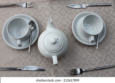 Two teacups and teapot on a dining table