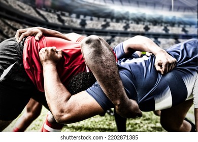 Two teams of multi-ethnic rugby players playing rugby at a sports stadium, wearing team strip, in a scrum, holding each other. Sport and competition concept digital composite. - Shutterstock ID 2202871385