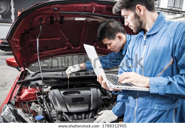 Two technicians are\
checking the availability of the car using a lab top to help with\
the operation.