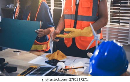 Two technicians inspect server racks in data center with tablet and fiber optic cable. Engineer and specialist discuss maintenance work in data center. Man and woman work together with safety equipmen