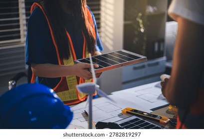 Two technicians inspect server racks in data center with tablet and fiber optic cable. Engineer and specialist discuss maintenance work in data center. Man and woman work together with safety equipmen