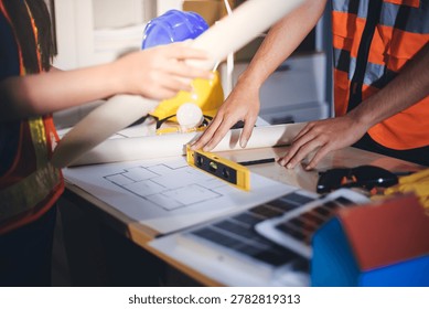 Two technicians inspect server racks in data center with tablet and fiber optic cable. Engineer and specialist discuss maintenance work in data center. Man and woman work together with safety equipmen